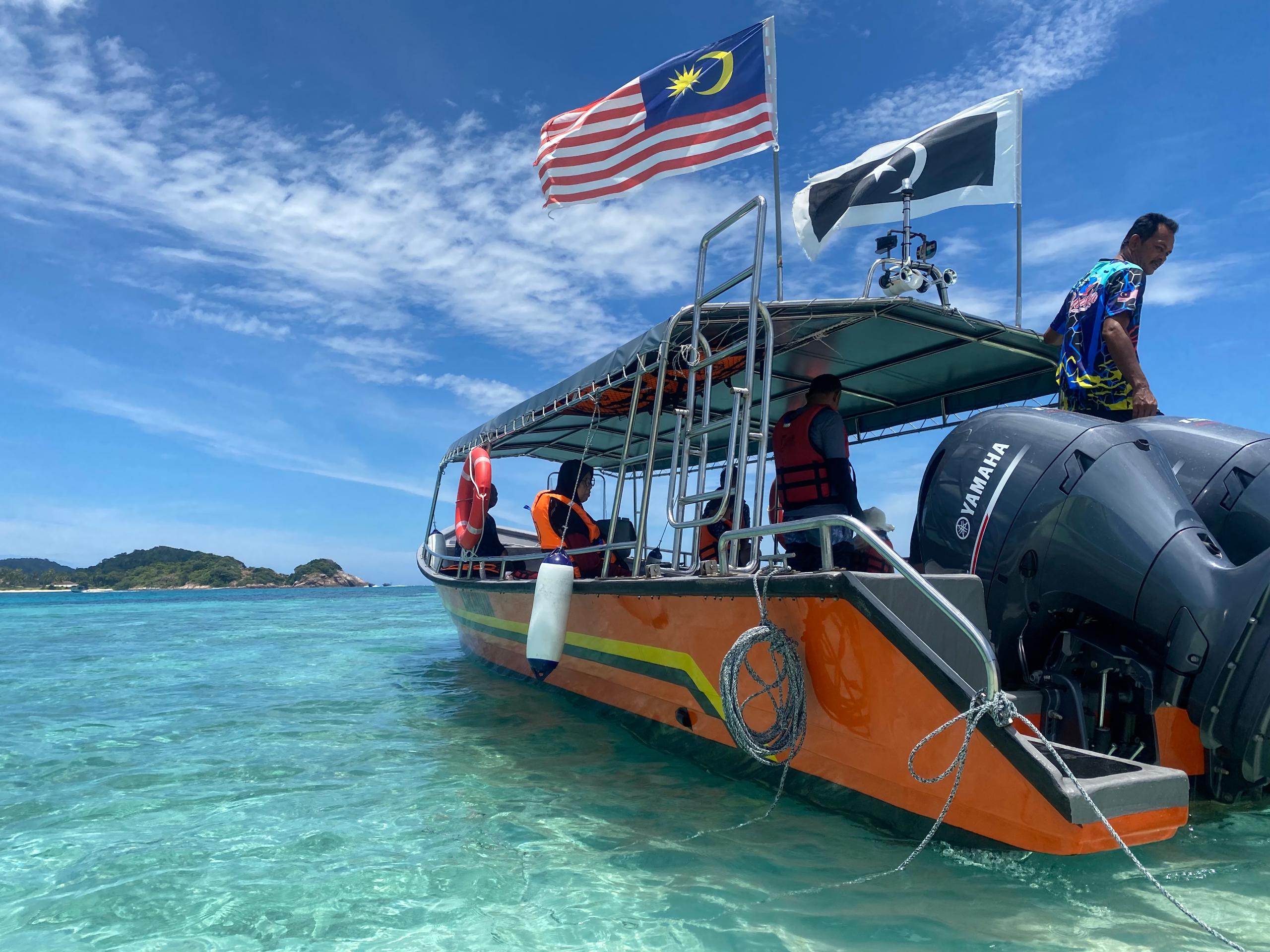 Pelancong berehat di atas bot laju semasa day trip ke Pulau Redang anjuran KOKANUN Travel.
